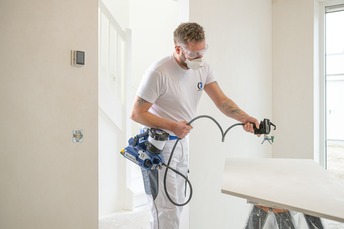 A decorator using the Graco Ultra Quickshot II on a white door