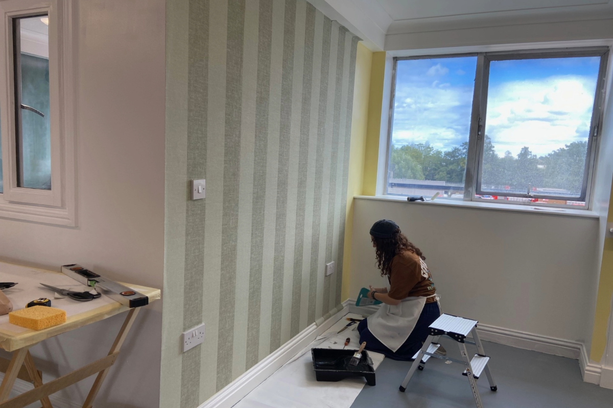 A course delegate finishing wallpapering a wall