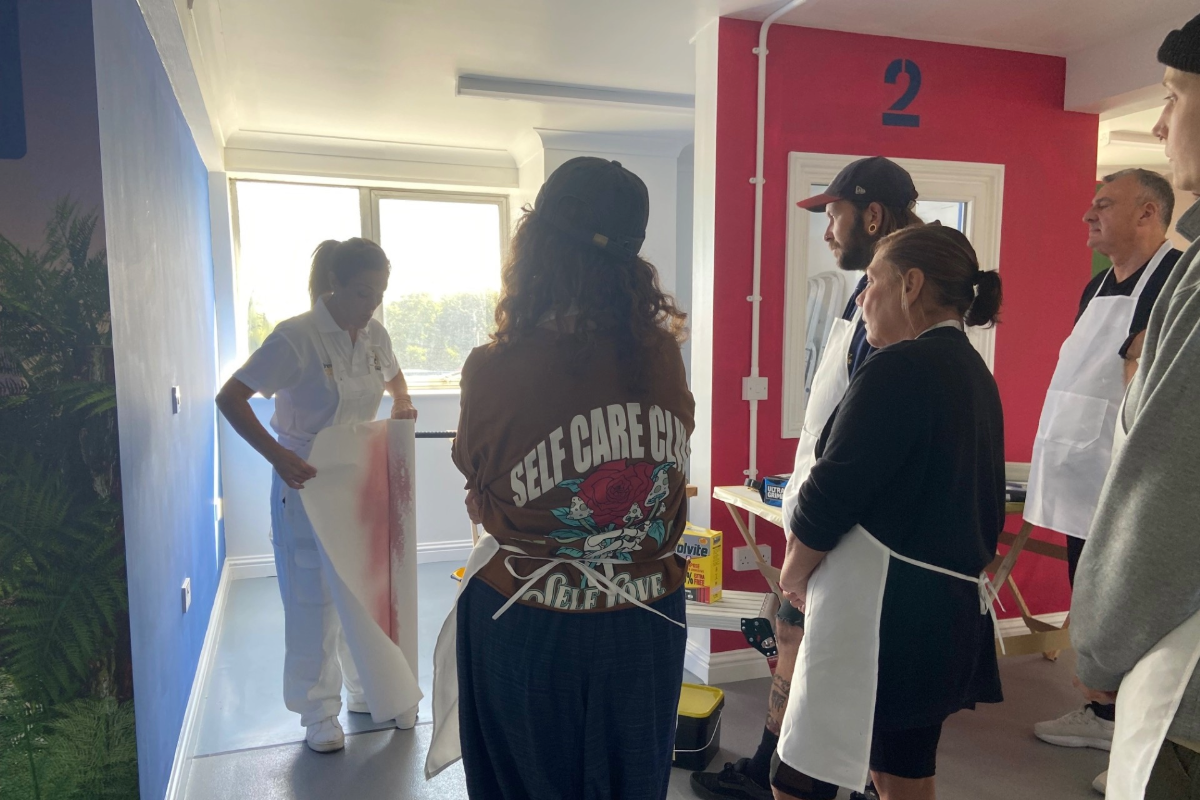 A group watching a roll of wallpaper being demonstrated